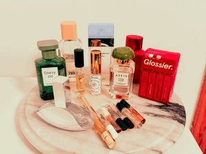 A marble platter sits on the top of a dresser with 9 perfume bottles, 6 sample vials, and a box with 4 more samples.